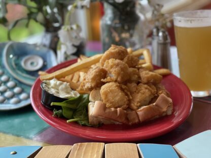 A pint of New Bedford scallops deep fried and loaded into a grilled hot dog roll, fries and tartar on the side