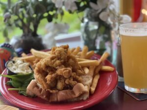 Fried clams with bellies packed into a buttery, grilled roll with tartar and fries on the side
